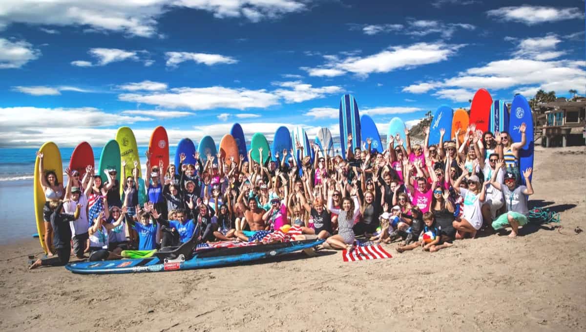 Große Gruppe von Apex-Social-Fachkräften mit Surfbrettern am Strand in Kalifornien
